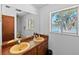 Bathroom with double sinks, wood cabinets, large mirror and a lake view window at 19254 Blount Rd, Lutz, FL 33558