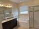 Bathroom featuring a soaking tub, tiled shower, and dark vanity with granite countertop at 19514 Sea Myrtle Way, Tampa, FL 33647