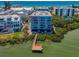 Scenic aerial view highlighting a condo building with balconies and a private dock, near lush greenery at 19925 Gulf Blvd # 503, Indian Shores, FL 33785