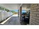 Carport featuring a black car parked under a covered area with brick columns and a white fence in the background at 2505 Minnehaha, Tampa, FL 33614