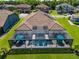 Aerial view featuring a large screened pool, tile roof, and manicured lawn at 28857 Picana Ln, Wesley Chapel, FL 33543