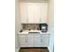 Convenient butler's pantry with white cabinets, quartz countertops, a bar station, and tiled backsplash at 28857 Picana Ln, Wesley Chapel, FL 33543