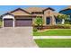 Charming home featuring a stone facade, well-manicured lawn, and a three-car garage at 28857 Picana Ln, Wesley Chapel, FL 33543
