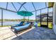 Relaxing covered patio with lounge chairs and a view of the pool and lake beyond at 28857 Picana Ln, Wesley Chapel, FL 33543