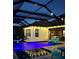 Backyard oasis with a luxurious pool, covered patio, and ambient lighting, perfect for evening relaxation and entertainment at 28857 Picana Ln, Wesley Chapel, FL 33543