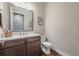Elegant powder room with a dark wood vanity, quartz countertop, and decorative mirror at 28857 Picana Ln, Wesley Chapel, FL 33543