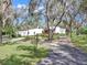 Attractive white home with a red door, a circular driveway, and mature landscaping at 2947 Cedar Trce, Tarpon Springs, FL 34688