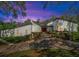 Twilight view of a modern home with colorful landscaping and a brick driveway at 2947 Cedar Trce, Tarpon Springs, FL 34688