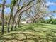 This grassy yard has trees overhead, a small house, and is very green at 2947 Cedar Trce, Tarpon Springs, FL 34688