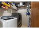 A compact laundry room featuring a washer, dryer, and shelving for organizing cleaning supplies at 3330 Foxridge Cir, Tampa, FL 33618