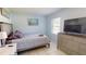 Bright bedroom with a queen bed, tiled floor, and chest of drawers under the TV at 5005 Puritan Rd, Tampa, FL 33617
