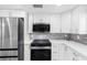 Updated kitchen features stainless steel appliances, white cabinets, tile backsplash, and quartz countertops at 5425 Bluepoint Dr, Port Richey, FL 34668