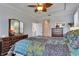 Bright main bedroom with a leaf-design ceiling fan, dark wood dresser and a colorful quilt-patterned bedspread at 5728 Sunset Falls Dr, Apollo Beach, FL 33572
