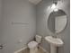 Cozy half bathroom with a pedestal sink, updated light fixture, and neutral gray paint at 6222 Trent Creek Dr, Sun City Center, FL 33573