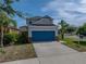 Inviting two-story home with a bright blue garage door, lush lawn, and mature palm trees at 6222 Trent Creek Dr, Sun City Center, FL 33573