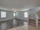 Spacious living room featuring gray wood floors, neutral walls, a ceiling fan, and stairwell access at 6222 Trent Creek Dr, Sun City Center, FL 33573
