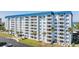 Exterior of the building shows balconies on all floors with mature palms in the landscape at 7 Elgin Pl # 510, Dunedin, FL 34698