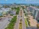 An aerial view showcases a busy city street with palm trees, buildings, and distant ocean views at 736 Island Way # 1101, Clearwater Beach, FL 33767