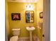 Yellow powder room with a pedestal sink, a commode, decorative art, and modern lighting at 750 4Th S Ave # 403C, St Petersburg, FL 33701