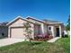 Charming single-story home with a well-manicured lawn, colorful landscaping, and an attached two-car garage at 811 College Leaf Way, Ruskin, FL 33570