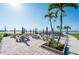 Outdoor community area with picnic tables, barbecue grills, and palm trees, overlooking the bay at 825 S Gulfview Blvd # 202, Clearwater Beach, FL 33767