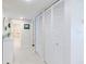 Hallway leading to the bathroom with white wood-look floors, a white storage cabinet, and closet space at 825 S Gulfview Blvd # 202, Clearwater Beach, FL 33767