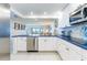 Updated kitchen with white cabinetry, stainless steel appliances, and a breakfast bar overlooking living area at 825 S Gulfview Blvd # 202, Clearwater Beach, FL 33767