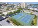 Aerial view of community tennis courts surrounded by lush landscaping and city skyline at 825 S Gulfview Blvd # 202, Clearwater Beach, FL 33767