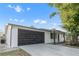 Charming single-story home featuring a stylish black garage door and well-maintained front yard at 9135 Suffolk Ln, Port Richey, FL 34668