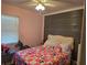 Bedroom with pink walls, a wooden accent wall, and a bed with a colorful comforter at 9950 Morris Bridge, Tampa, FL 33637