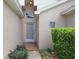 Front entrance featuring a glass-paneled storm door, beige stucco, and lush landscaping at 10509 Deepbrook Dr, Riverview, FL 33569