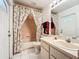 Bathroom features a vanity, toilet, tub with shower and floral curtains, and white tiled flooring at 11216 Longbrooke Dr, Riverview, FL 33579
