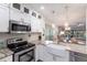 Bright kitchen featuring white cabinets, stainless steel appliances, granite counters, and adjacent dining area at 11531 Shipwatch Dr # 1030, Largo, FL 33774