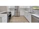 Modern kitchen featuring stainless steel appliances, white cabinetry, quartz countertops, and wood-look flooring at 1155 Withlacoochee St, Safety Harbor, FL 34695