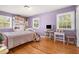 A cozy bedroom featuring hardwood floors, purple walls, built-in shelves, and natural light from two windows at 1211 S Druid Ln, Tampa, FL 33629