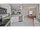 Open kitchen area with white cabinets, stainless steel appliances, counter seating and a view of the dining and living areas at 1216 Lyndhurst Greens Dr, Sun City Center, FL 33573