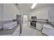 Well-lit kitchen with stainless steel appliances, white cabinets and tile floors, leading to laundry room at 1216 Lyndhurst Greens Dr, Sun City Center, FL 33573