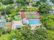 Aerial view of a community featuring swimming pools, tennis courts, and a basketball court surrounded by lush greenery at 134 Sycamore Ln # H, Oldsmar, FL 34677