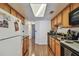Galley kitchen featuring wood cabinets, black countertops, stainless steel sink, and hardwood floors at 134 Sycamore Ln # H, Oldsmar, FL 34677