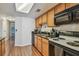 Galley kitchen featuring wood cabinets, black appliances and countertops, and hardwood floors at 134 Sycamore Ln # H, Oldsmar, FL 34677