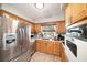 Traditional kitchen with stainless steel refrigerator, appliances, light wood cabinets, and a bright window at 1399 Leeward Ave, Spring Hill, FL 34606