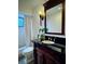 Elegant bathroom vanity with dark countertop, decorative mirror, and classic lighting fixture at 14678 Village Glen Cir, Tampa, FL 33618