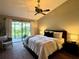 Inviting bedroom with a ceiling fan, sliding glass door to the patio, and tranquil backyard views at 14678 Village Glen Cir, Tampa, FL 33618