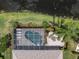 Aerial view of the enclosed pool, patio, landscaping, and pond behind the house at 18714 Chemille Dr, Lutz, FL 33558