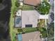 An overhead view featuring a screened pool, solar panels, a patio area, and water views at 18714 Chemille Dr, Lutz, FL 33558