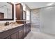 Bathroom featuring double vanities with marble countertops and decorative dark wood cabinets with a large shower at 18714 Chemille Dr, Lutz, FL 33558