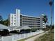Condo complex with white exterior, covered parking, white picket fence, palms, and blue skies at 200 N Betty Ln # 5F, Clearwater, FL 33755