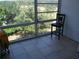 Bright sunroom with tiled flooring, a large picture window showcasing lush greenery, and a classic chair for relaxation at 200 N Betty Ln # 5F, Clearwater, FL 33755