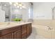 Bright bathroom featuring double sinks, a soaking tub, a separate shower, and neutral tile at 20203 Merry Oak Ave, Tampa, FL 33647