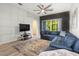 Cozy living room with a comfortable blue sectional, large windows, and a modern entertainment center at 20203 Merry Oak Ave, Tampa, FL 33647